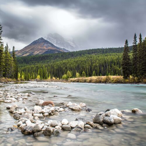 Photo of Alberta landscape looking at a river with a mountain in the background.