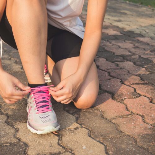 person kneeling down tying their shoes