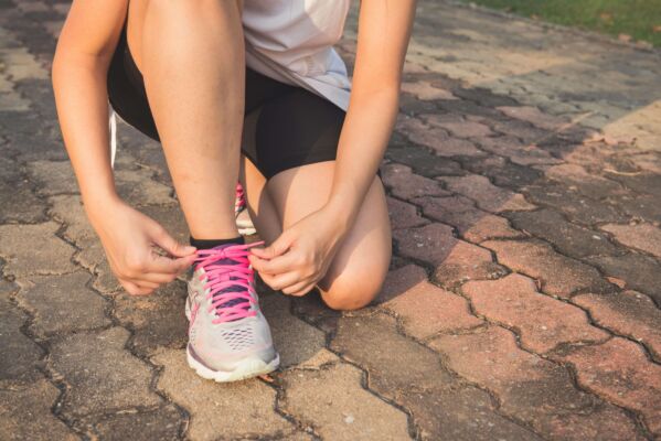 person kneeling down tying their shoes