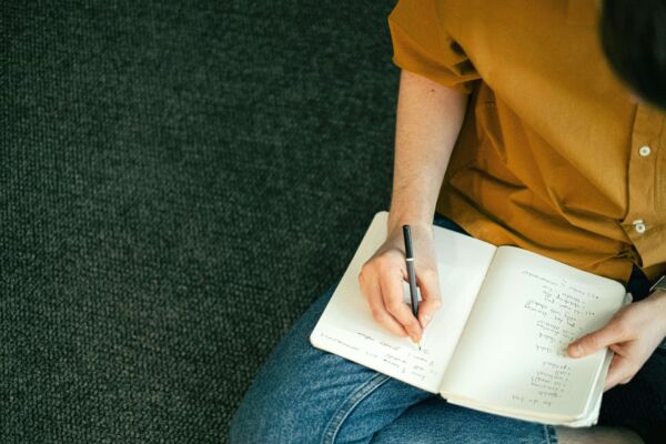 person sitting writing in a notebook